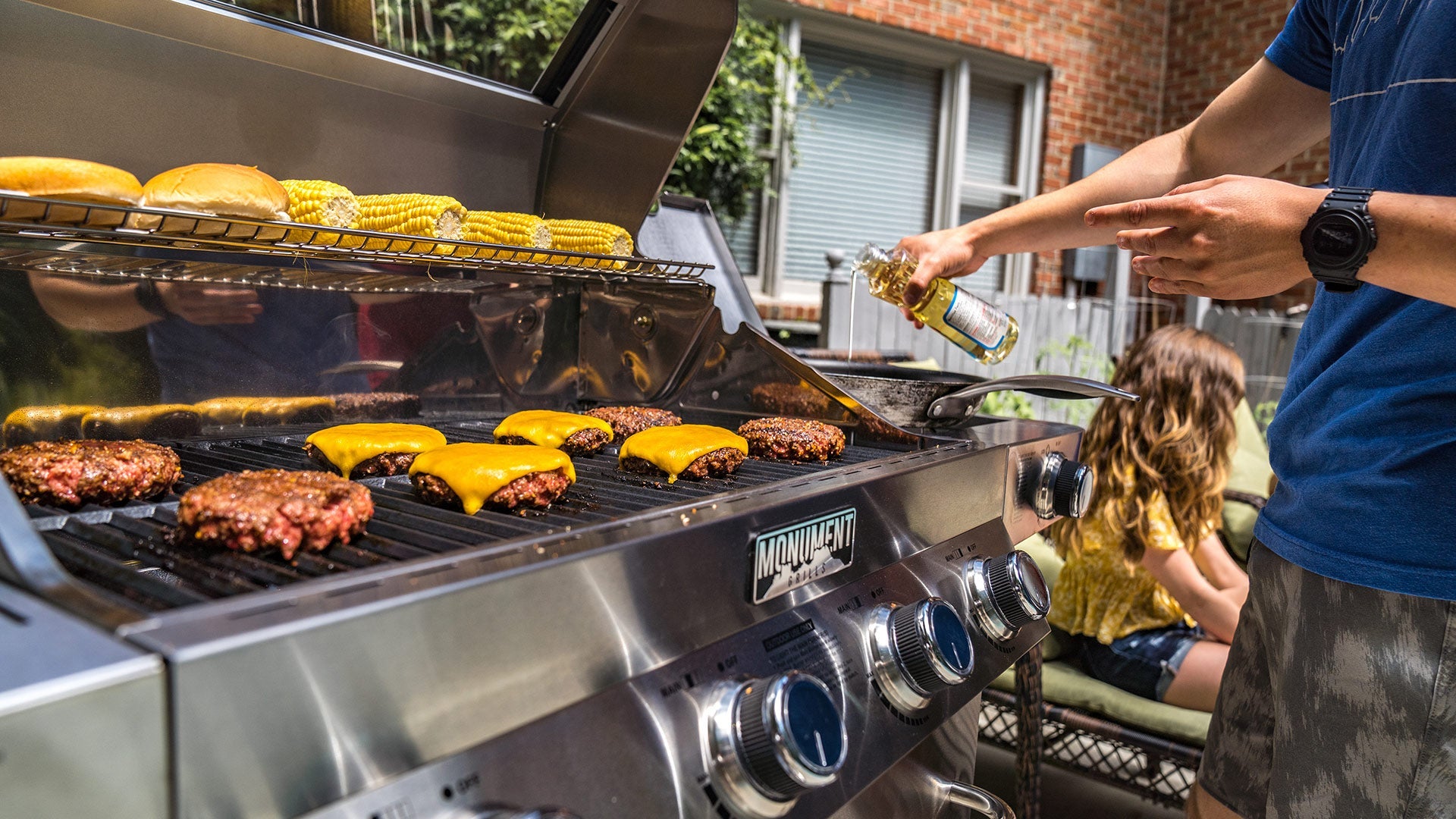 Man and son grilling together on a Monument Grills gas grill in a backyard